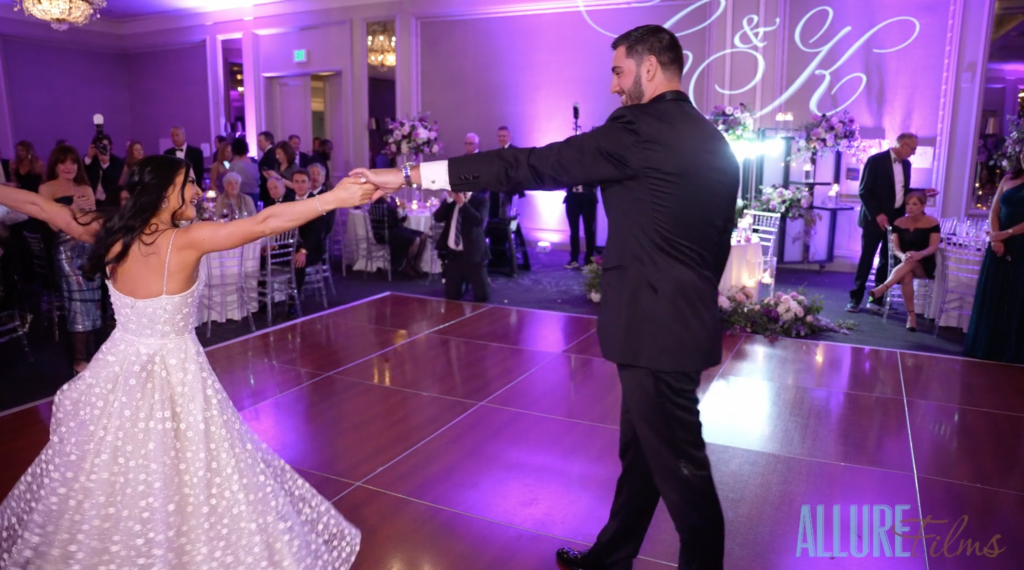 Chloe and Kyle dance on the ballroom floor lit with gorgeous pink lighting.