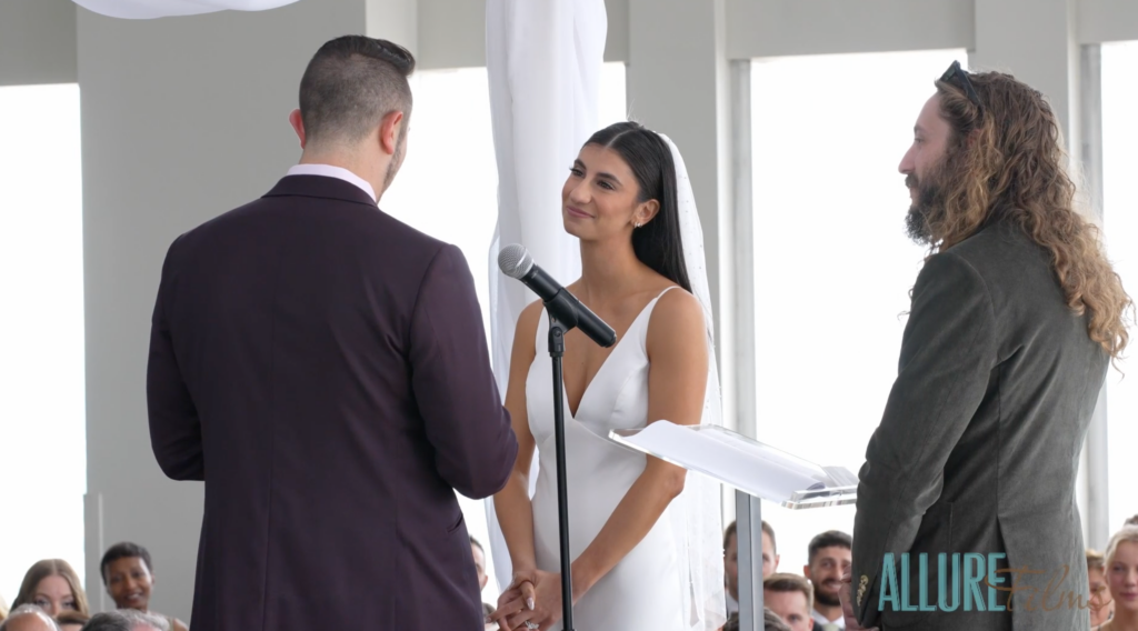 Alex saying vows to Caroline, who listens and smiles.